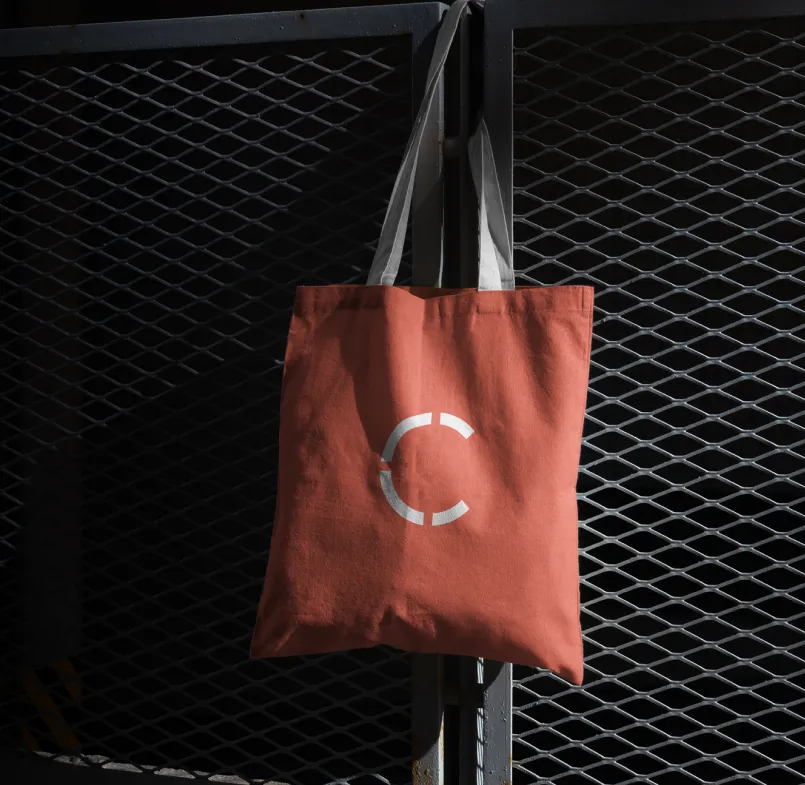 Mockup of burnt orange coloured tote bag with white Commonfuture motif in the centre.